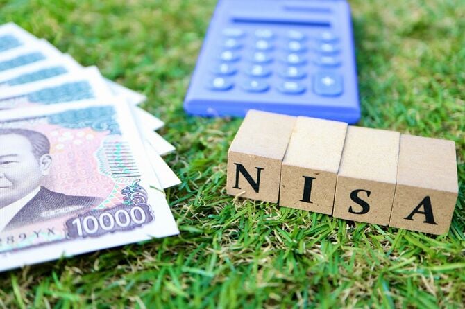 NISAと書かれた木製ブロックと電卓、1万円札の束
