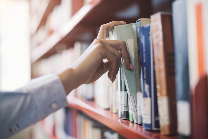 図書館の棚から本を取る人の手