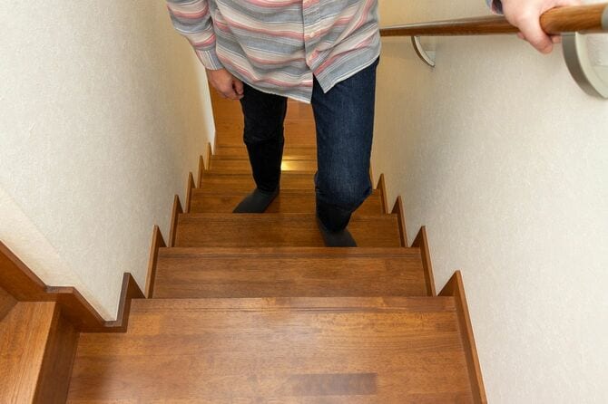 手すりを掴んだまま階段を上る男性