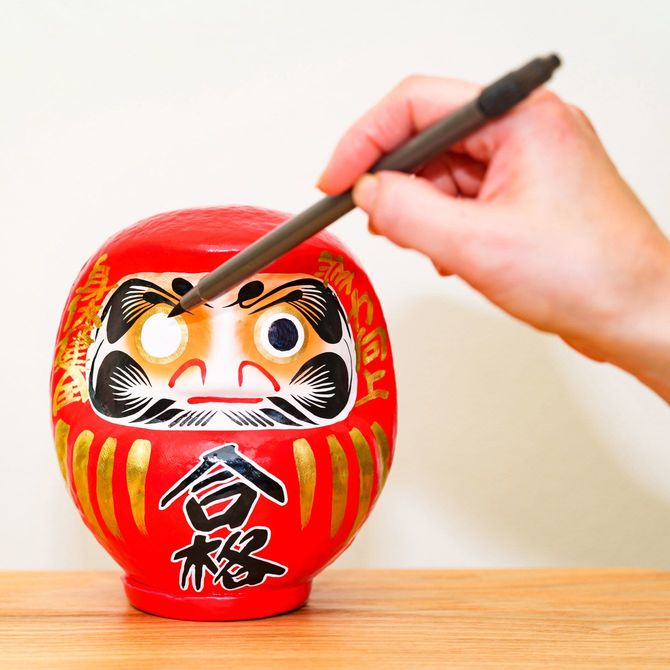 入試の勝利を願ってだるまの左目に墨を入れる