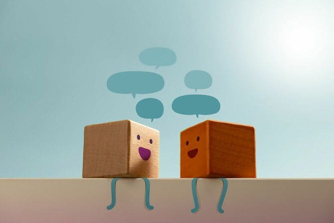 会話の吹き出しを浮かべる顔の書かれた木製ブロック