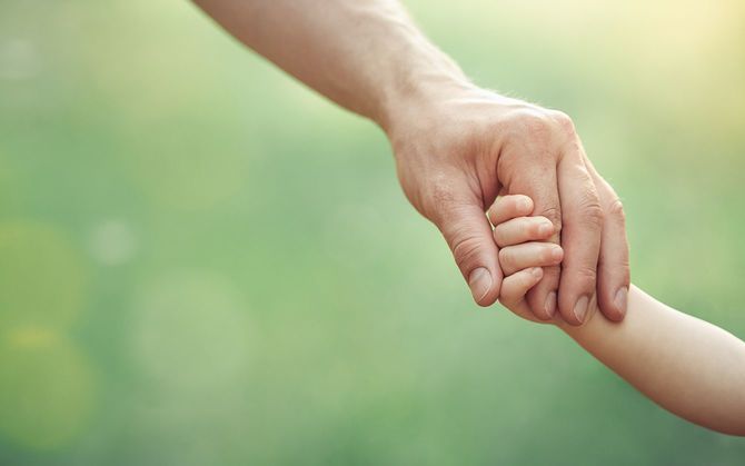 晴れた日の屋外で幼い子供を抱きしめる父親の手