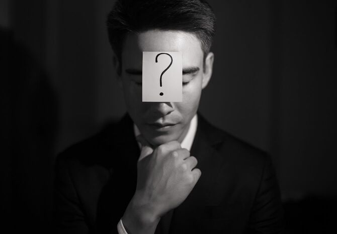疑問符の記号を持つビジネスマン