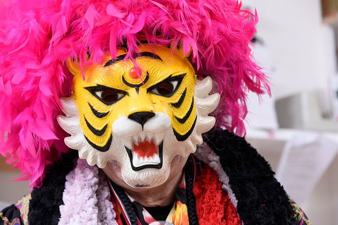 ピンクアフロのカツラにタイガーのお面をつけた人