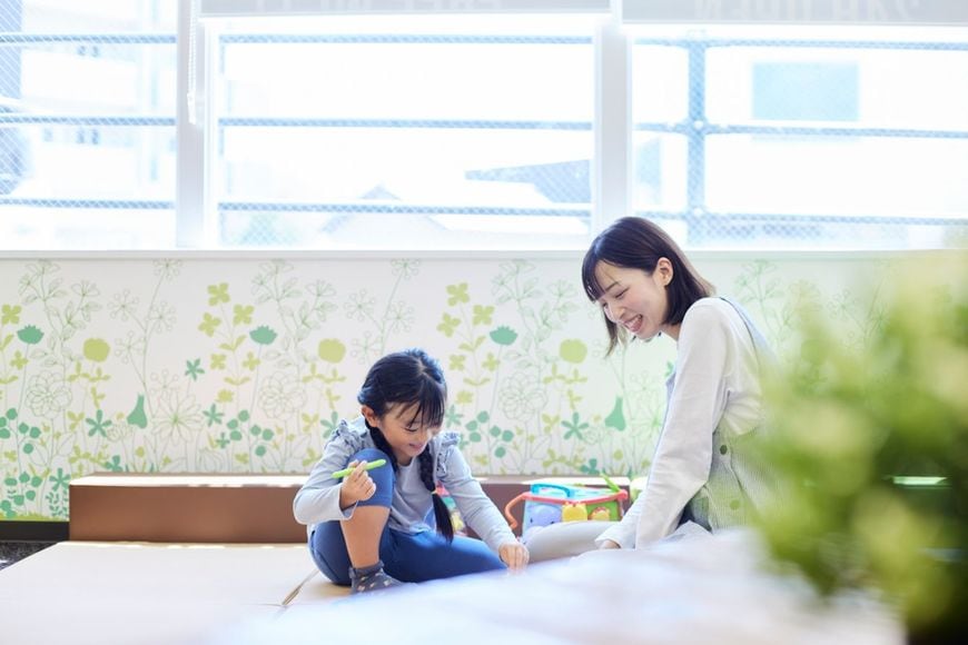 子どものお絵かきを見守る保育士