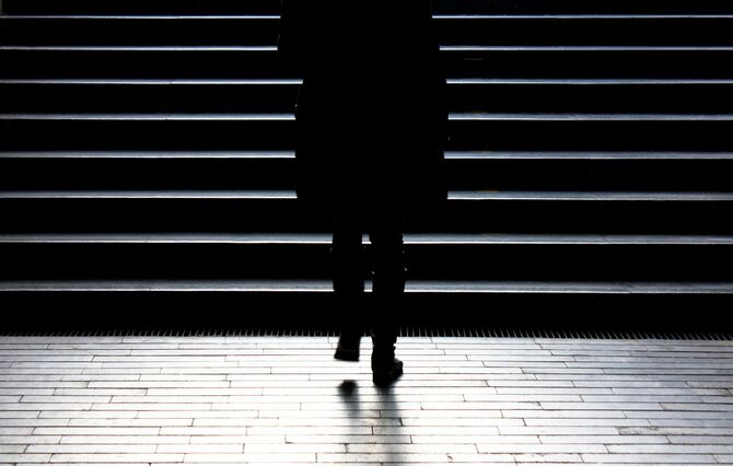 冬の月明かりに照らされた階段を一人で上がる女性のシルエット