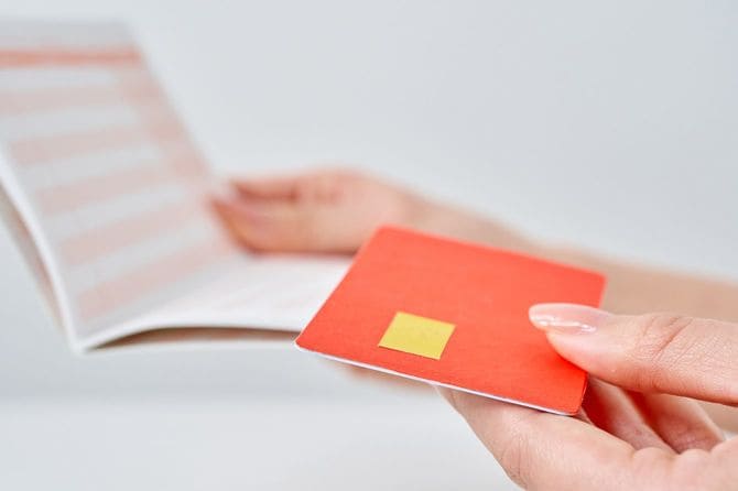 通帳とクレジットカードを見比べている女性の手元