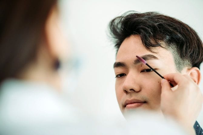 美容院で眉毛を整えてもらっているアジア人男性