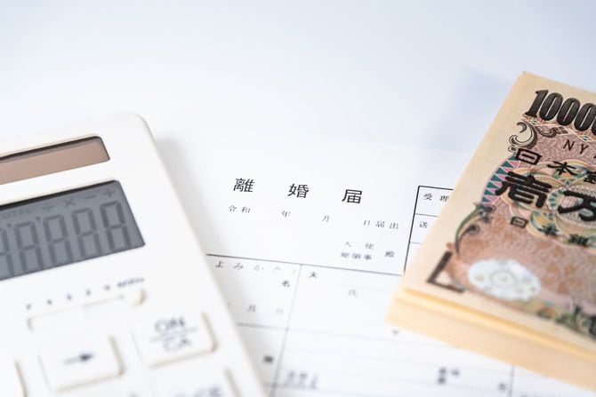 離婚届の上に置かれた電卓とたくさんの一万円札