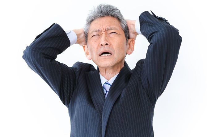 頭を抱える年齢を重ねたビジネスマン