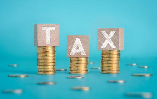 積み上げられたコインの上のTAXの文字