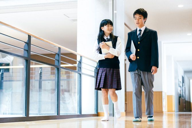 学校の廊下を話しながら歩く男子と女子生徒
