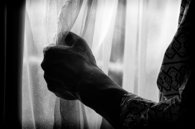 レースのカーテンを握りしめている、浴衣着用の女性の手元