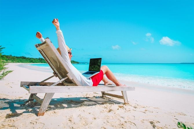 若い男がビーチでラップトップ