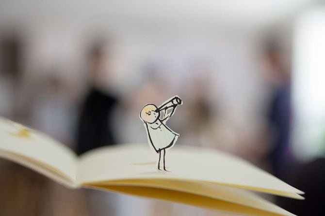 冊子の上で、双眼鏡を覗く子供