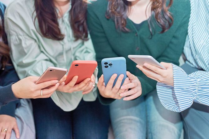 スマートフォンを見ながら話す女性