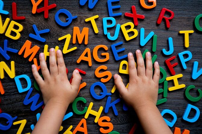 カラフルなアルファベットのおもちゃを触る子どもの手