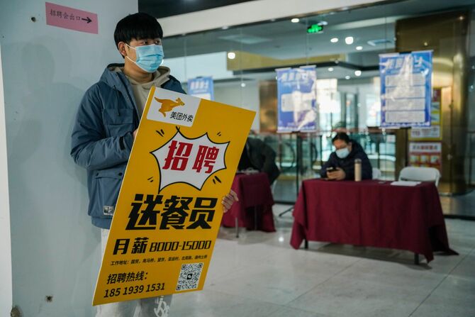2023年2月24日、中国・北京で開催されたジョブフェアで、マスクをつけた男性が求人広告を手にする。中国人力資源・社会保障部は、新型コロナの制限により過去3年間オンラインになっていたが、2月に全国で数百のジョブフェアを開催すると発表した。