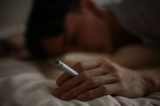 ベッドでタバコを吸う男性