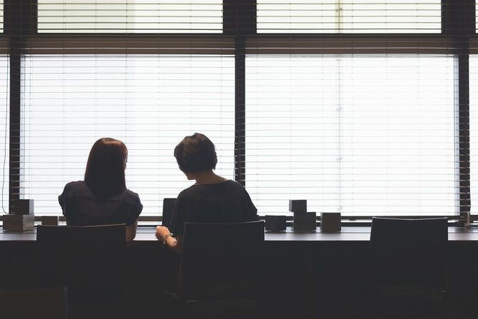 オフィスの窓際のカウンター席で話をする2人