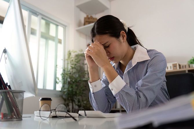 デスクでストレスと疲労に苦しむ女性