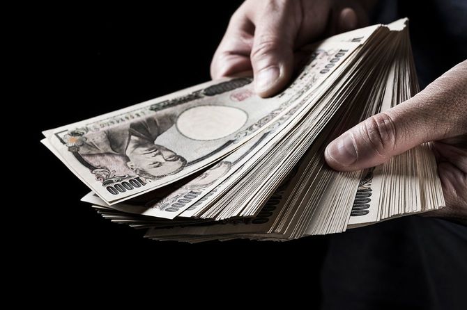 日本の1万円札の山を持つ男。