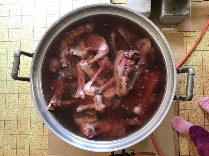 大鍋で熊の骨をグツグツと煮る