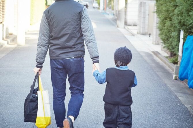 子供の手を引いて歩く父親