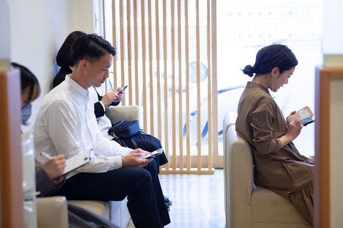 患者は、医師の診察室の待合室でソファで順番を待っています。