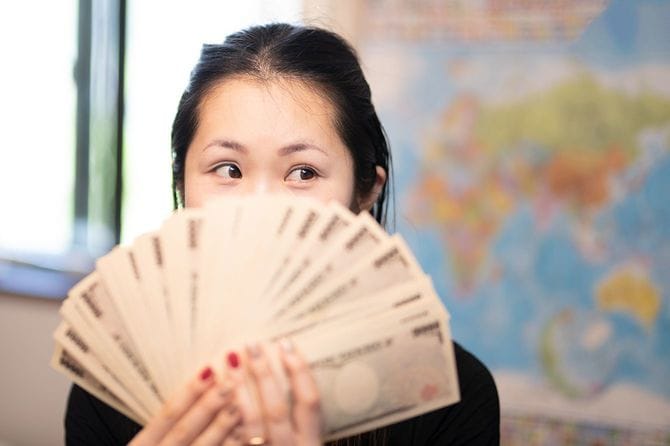 お金を数えて微笑む女性