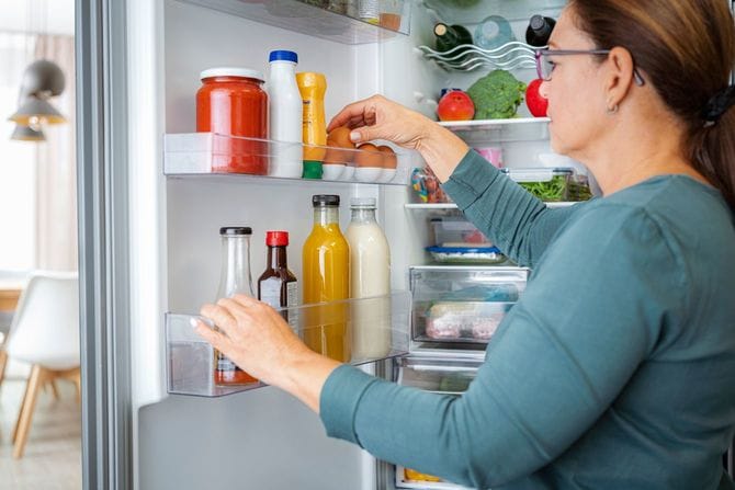 冷蔵庫のドアから卵を取り出す女性