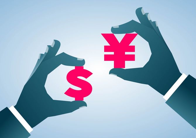 右手に円記号、左手にドル記号を持つ手元