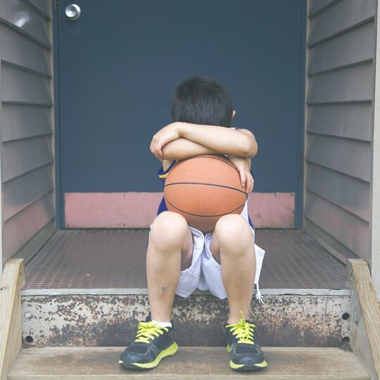バスケットボールを抱えて座り込む男児