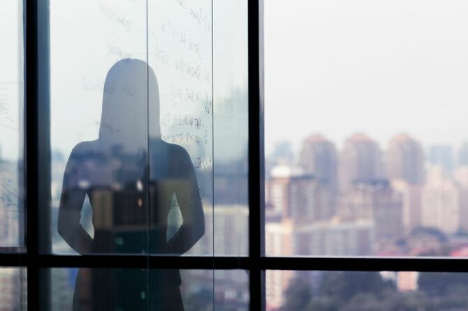 ガラス張りのオフィスから街を眺めている女性