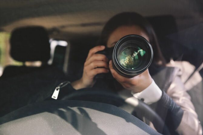 車の中からスクープ写真を狙うカメラマン