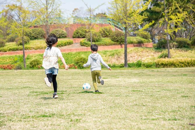 公園でサッカーボールで遊ぶ2人の子ども