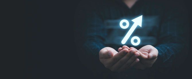 上向きの矢印のついたパーセント記号の灯を手のひらで大事にする男性の手元