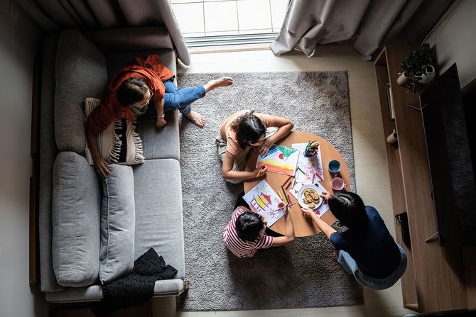 家で絵を描く娘にクッキーを配る母親