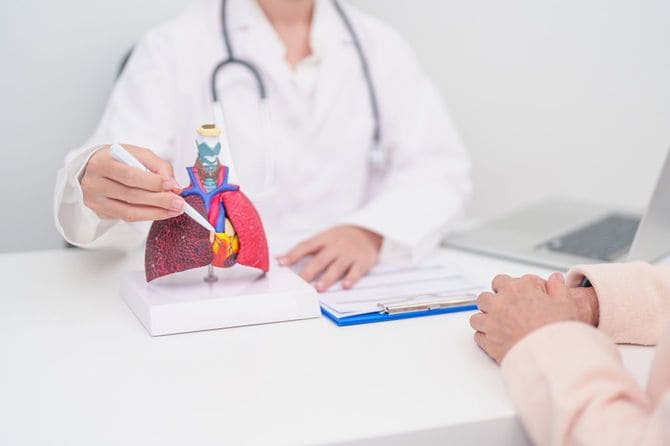 ペンで模型の心臓を指しながら説明している医師