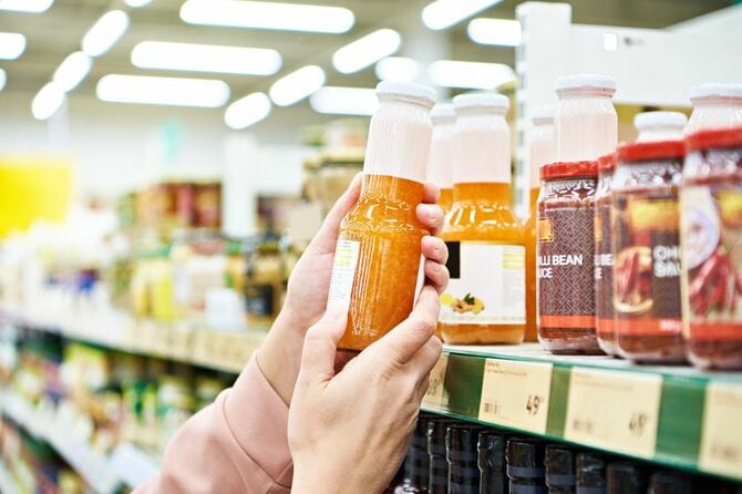 スーパーの棚で珍しい瓶を手に取っている手元
