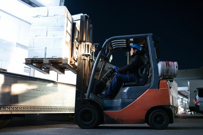 フォークリフトを操作してトラックに荷物を積み込む男性