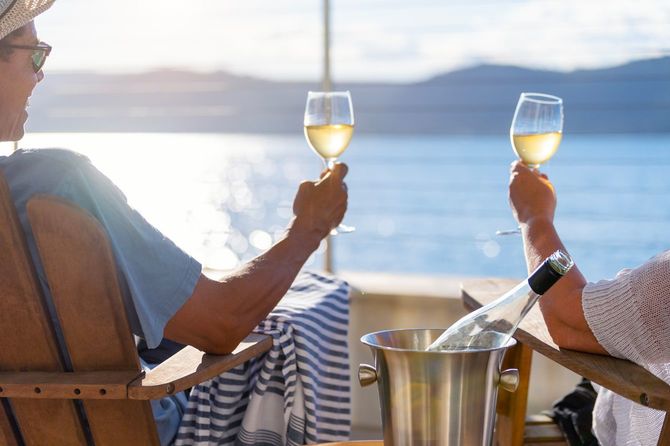 湖に向かって白ワインで乾杯する二人の男性