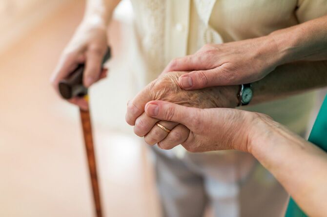 高齢患者の手を握る医療者の手