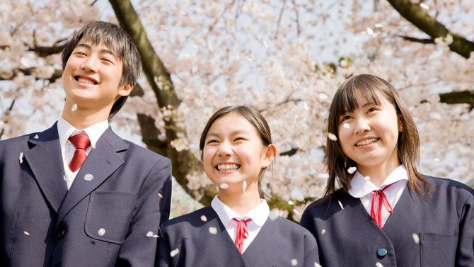桜の花の下で笑顔を見せる高校生たち