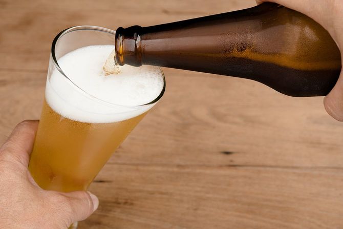 ガラス瓶からビールを注ぐ手
