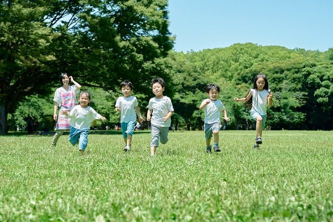 走る子どもたちと見守る女性