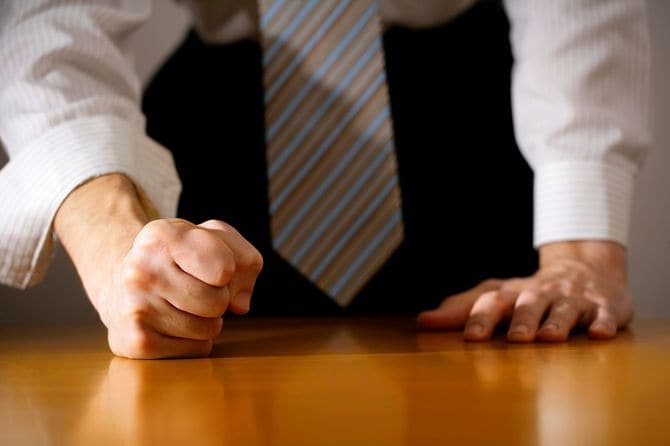 握りこぶしでテーブルを打つビジネスマン