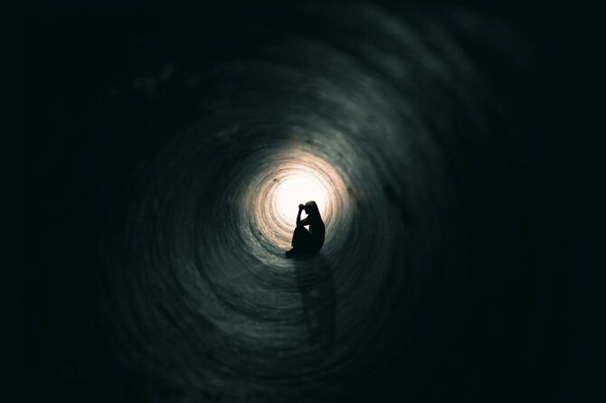 暗くて長いトンネル内で座り込んでいる女性のシルエット
