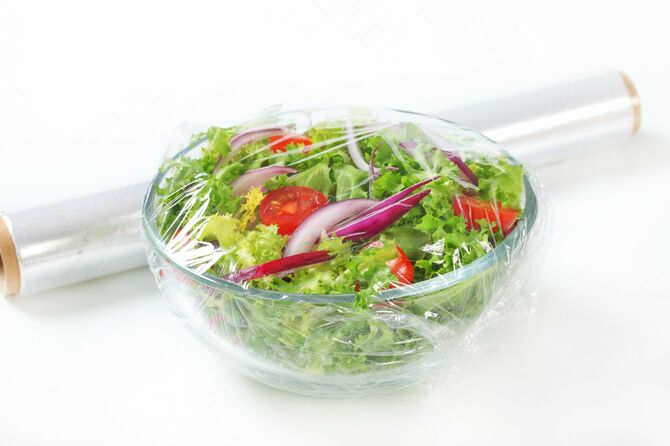 ラップで覆われたガラスボウルの新鮮な野菜サラダ