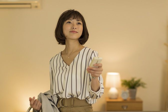 エアコンをつける女性